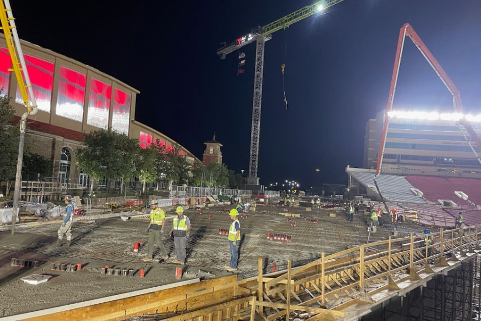 A group of construction workers are working on a construction site at night.