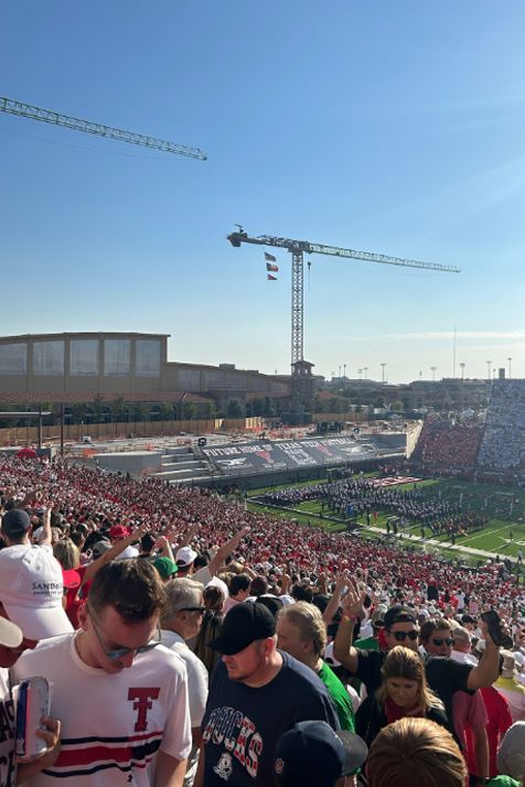 A crowd of people are standing in a stadium with a crane in the background.