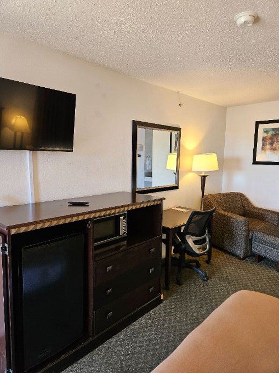 Hotel room with TV, dresser, desk, chair, couch, and lamp