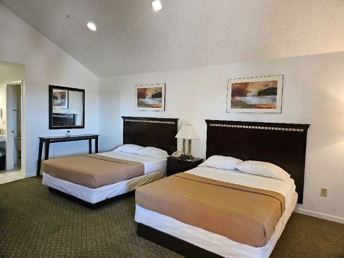 Hotel room with two beds, art, and a small table