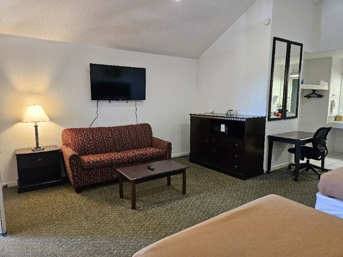 Hotel room with sofa, TV, dresser, desk, and bed