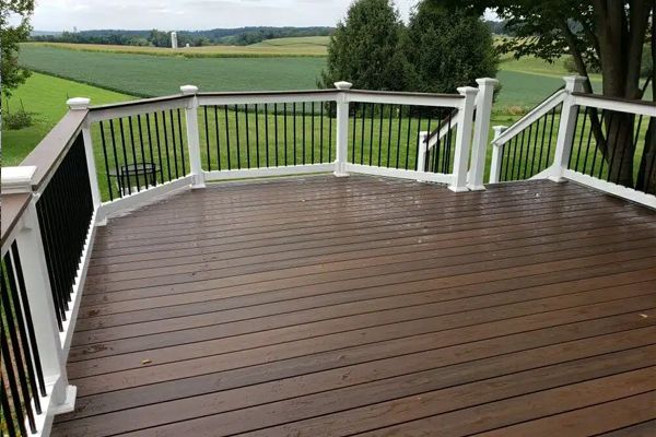 a wooden deck with a white railing and a view of a field