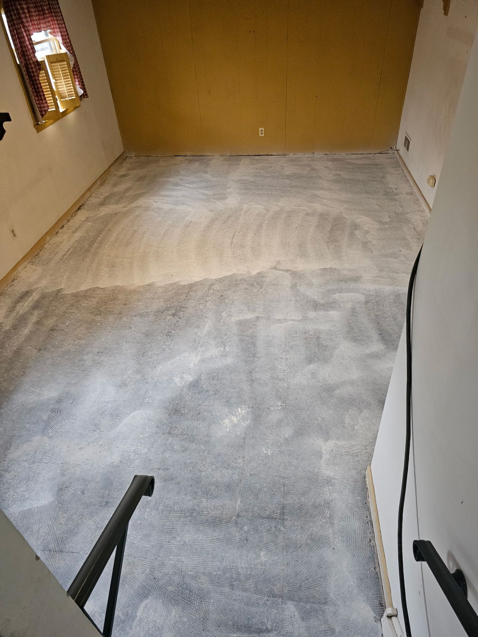 Empty carpeted room with beige walls and stairs leading down in the foreground