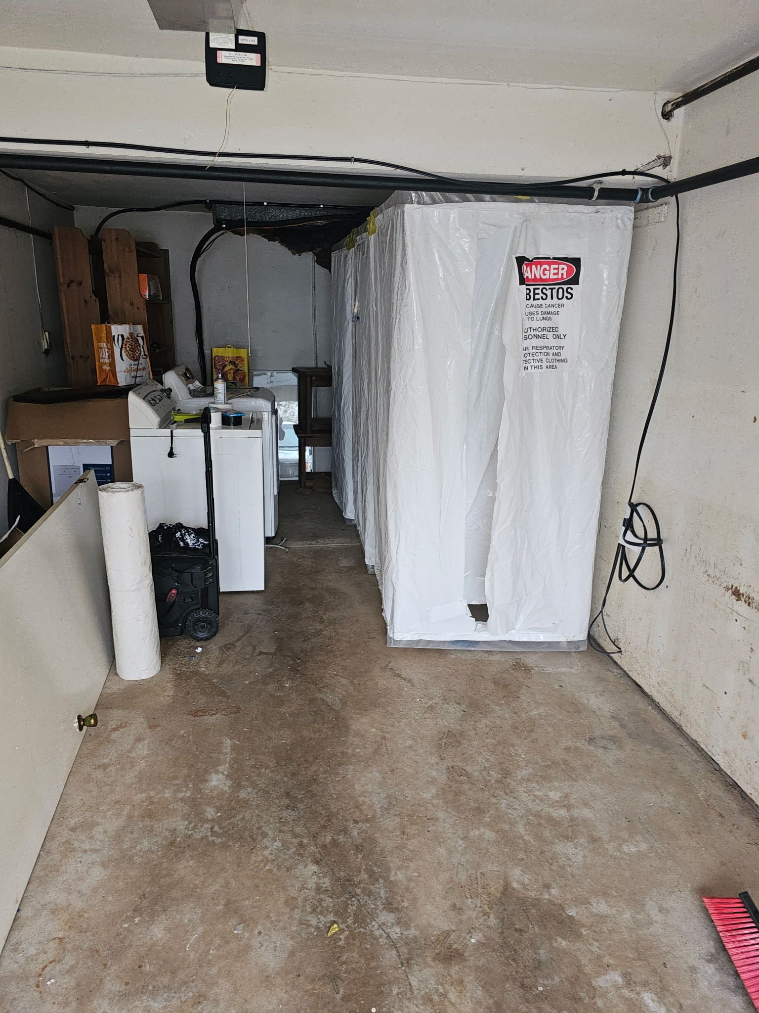 Garage interior with white appliances, storage items, and a concrete floor.