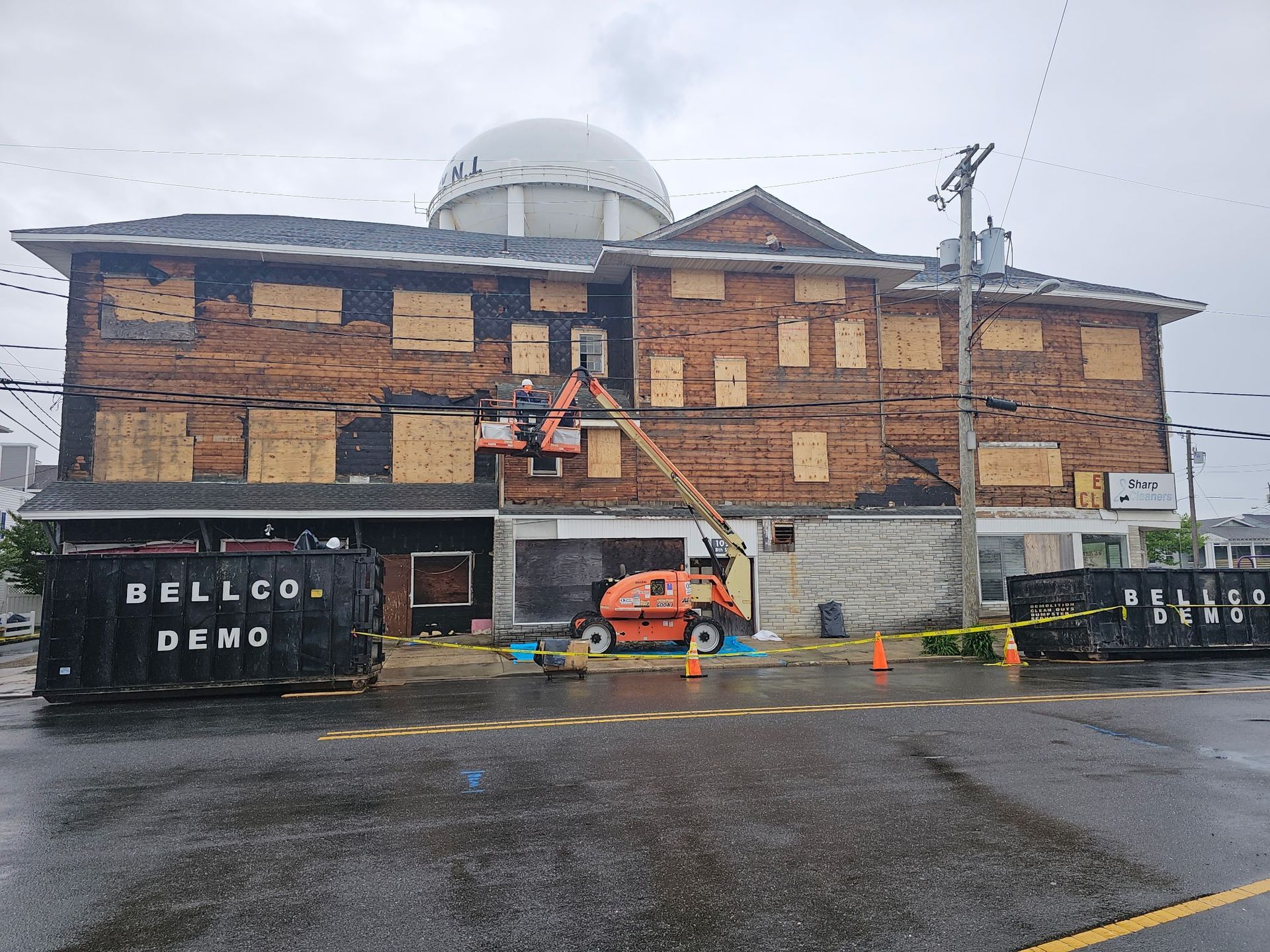 Historic brick building under renovation on a rainy day, with scaffolding, cones, and construction equipment.