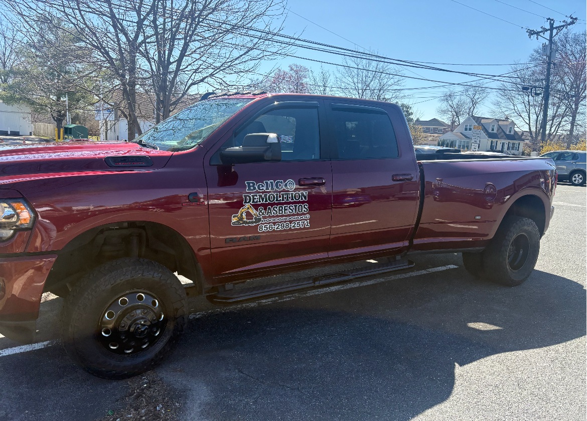 Maroon pickup truck parked outdoors on a sunny day, with white lettering on the driver’s door.