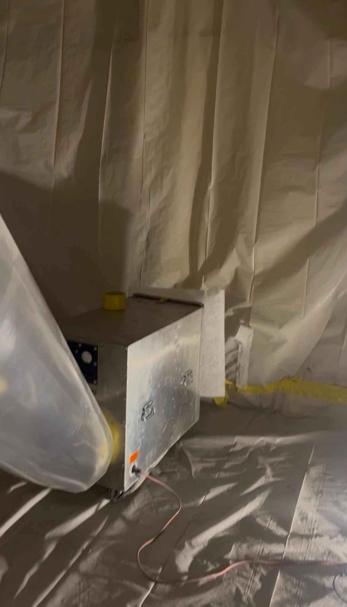 Painted room under construction with plastic sheeting, a step stool, and covered floors.
