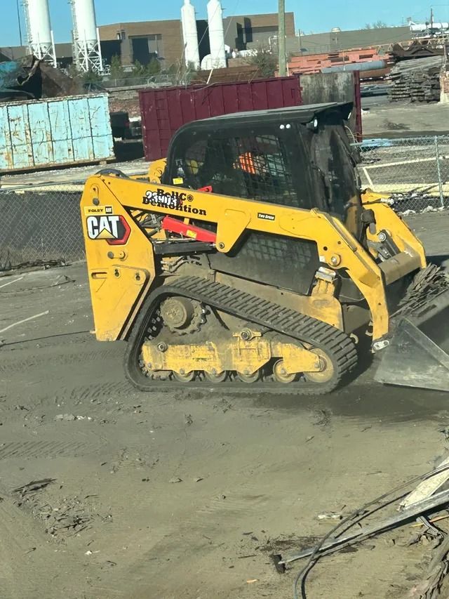 Yellow CAT skid steer parked on a construction site beside concrete and dirt.