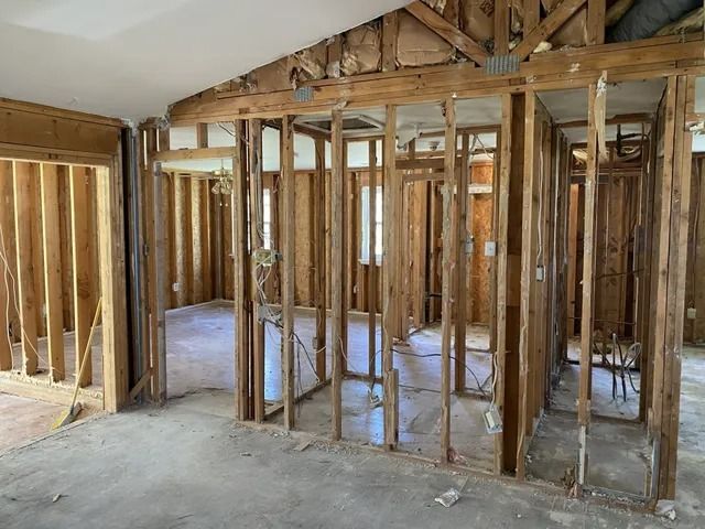 Unfinished interior with exposed wooden framing and concrete floor in a house under construction