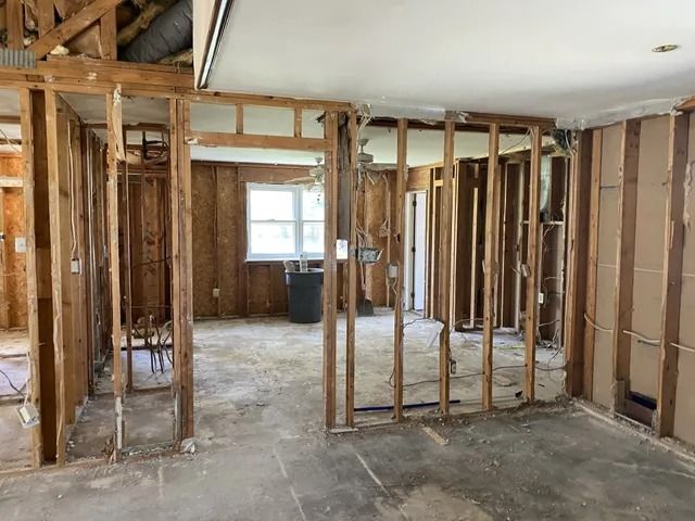Interior of a house under renovation, with exposed wooden framing and unfinished walls and floors.
