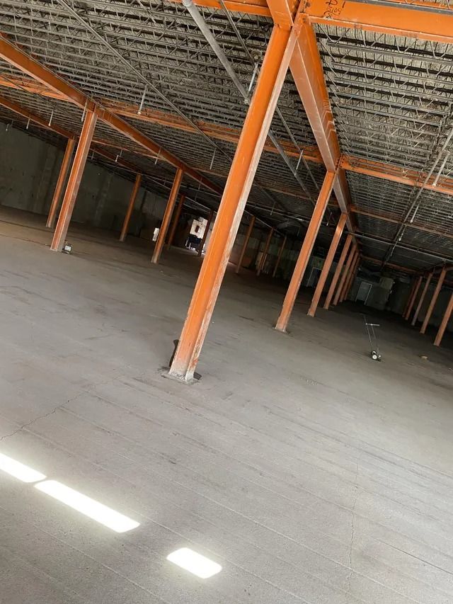 Empty warehouse interior with orange support columns and a concrete floor under a metal roof