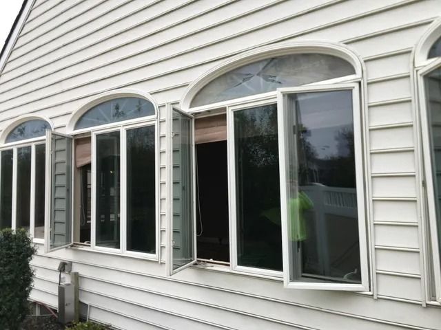 White house exterior with three arched windows and open shutters on a beige-sided wall