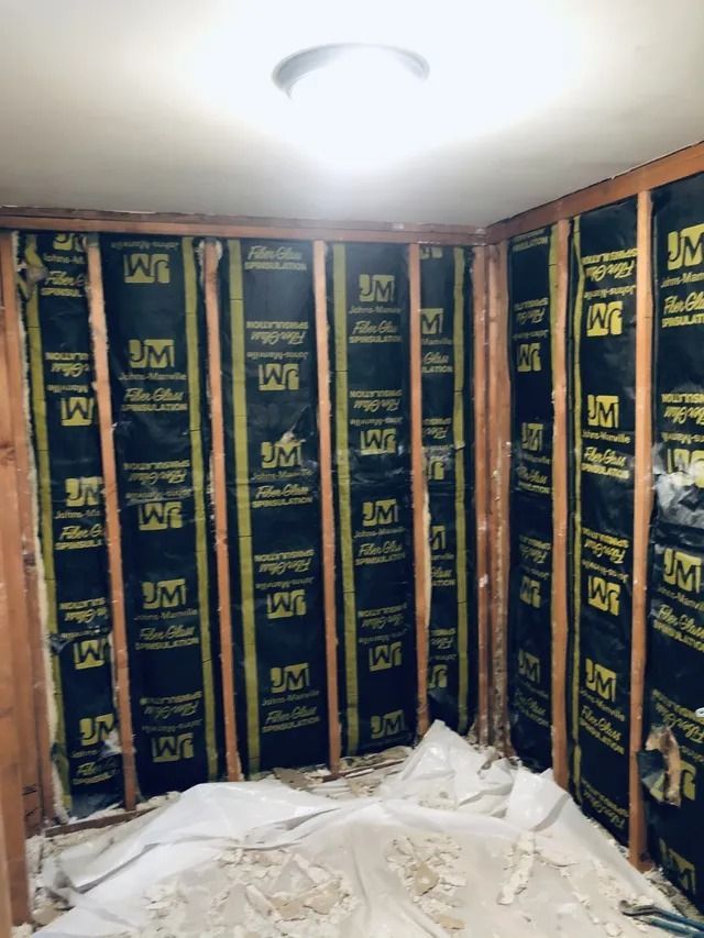 Partially finished room with black-and-gold wall panels and a ceiling light, floor covered in protective sheeting
