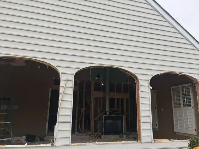 Partially gutted house exterior with three arched garage openings and exposed framing