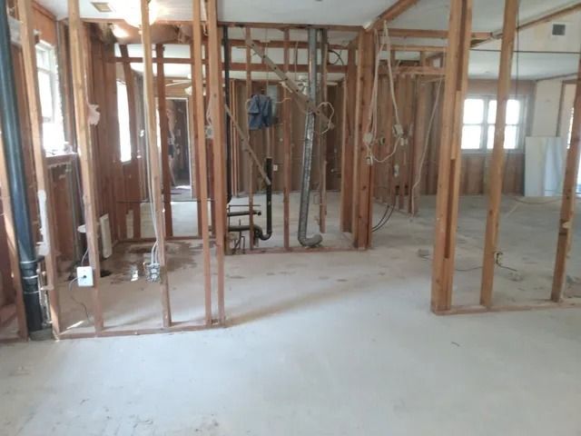 Interior under construction with exposed wooden framing and unfinished concrete floor
