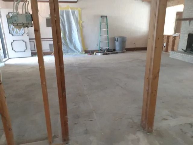 Unfinished room with exposed wooden studs, concrete floor, and a ladder against the back wall.