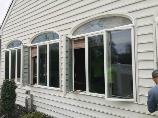 White house exterior with large arched windows, one open, and a person partially visible at right