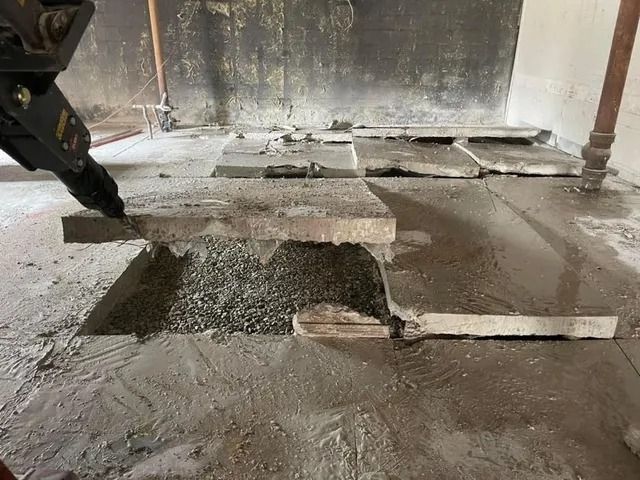 Partially poured concrete floor in a rough indoor construction site, with fresh wet patches and exposed edges