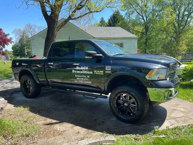 Dark pickup truck with company lettering parked in a driveway beside a garage and trees