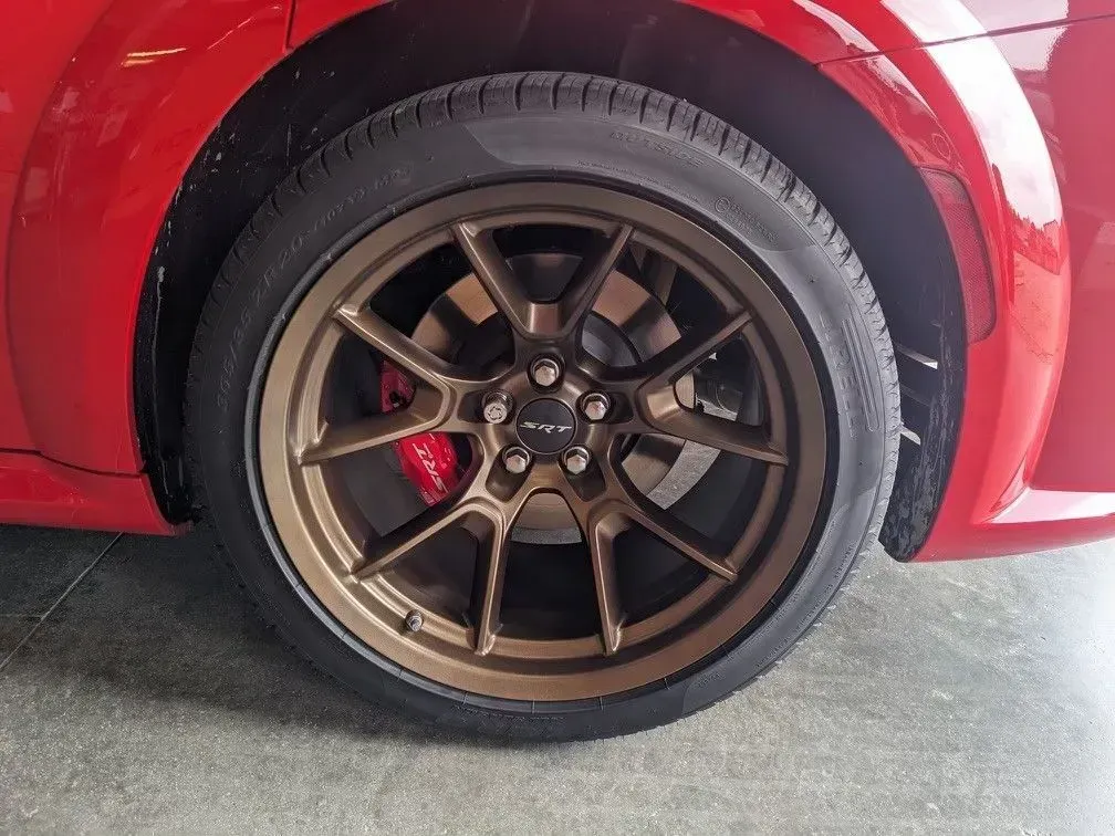 Bronze-colored multi-spoke car wheel on a red vehicle, showing a red brake caliper inside.