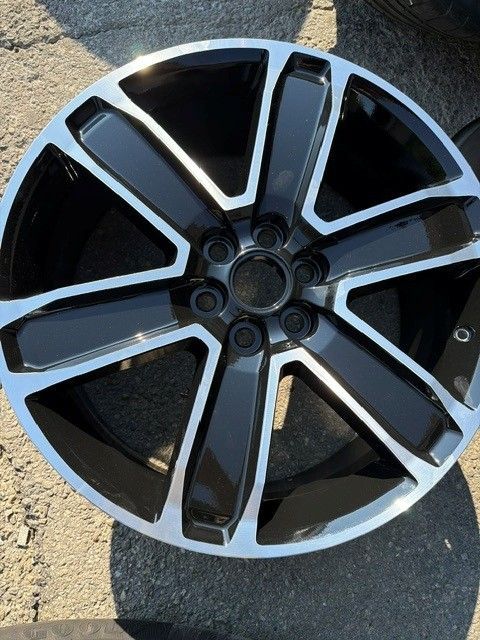 Black-and-silver alloy car wheel rim on pavement, seen close up
