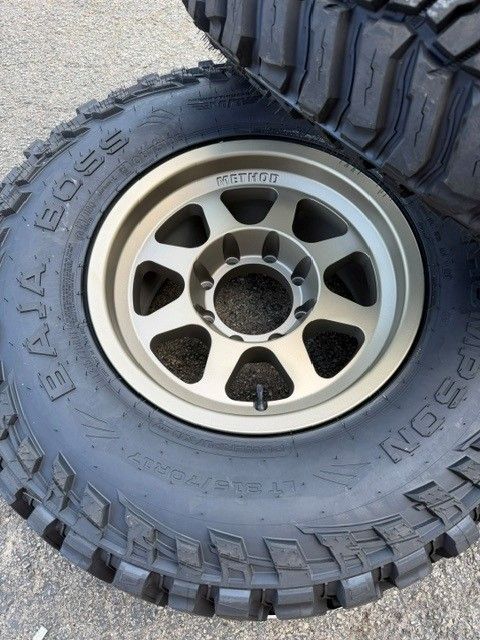 Off-road tire mounted on a silver alloy wheel, viewed close up.