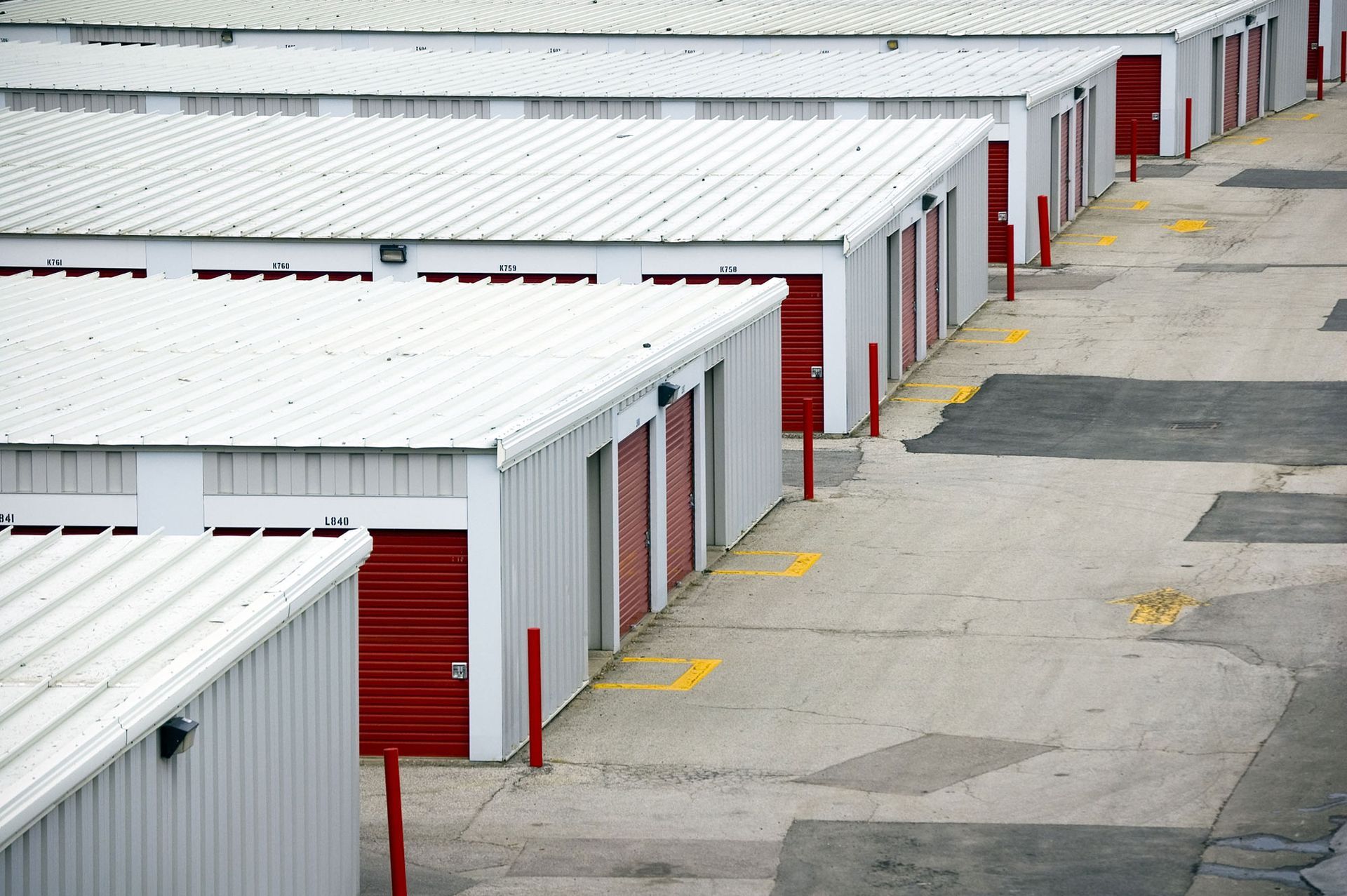 A row of storage units with red doors and white roofs