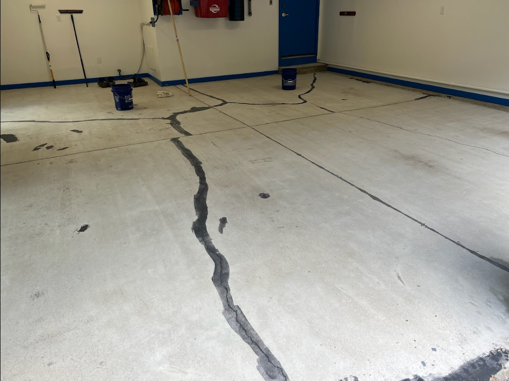 Concrete garage floor with a long dark crack or seal line running across it.