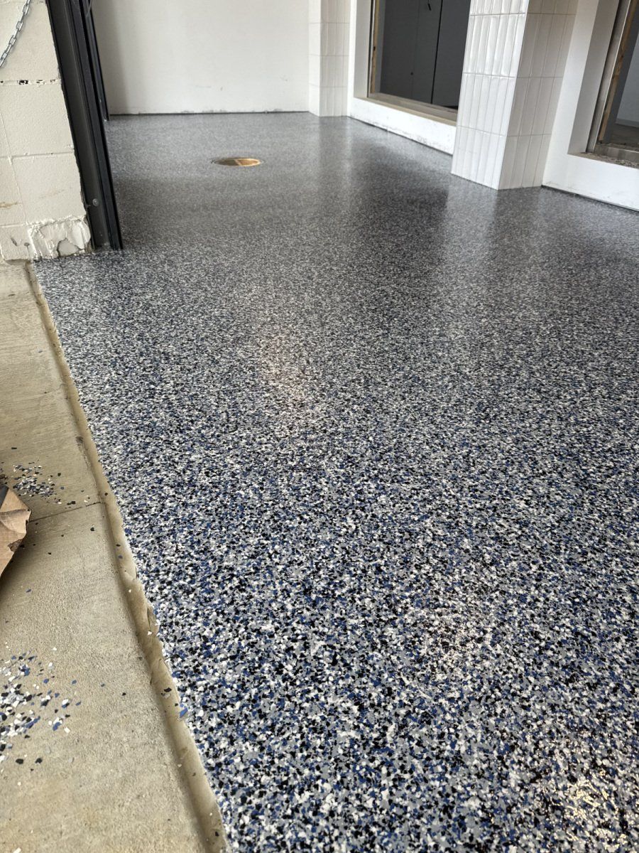 A glossy grey, white, and black speckled epoxy floor covering the interior of a garage.