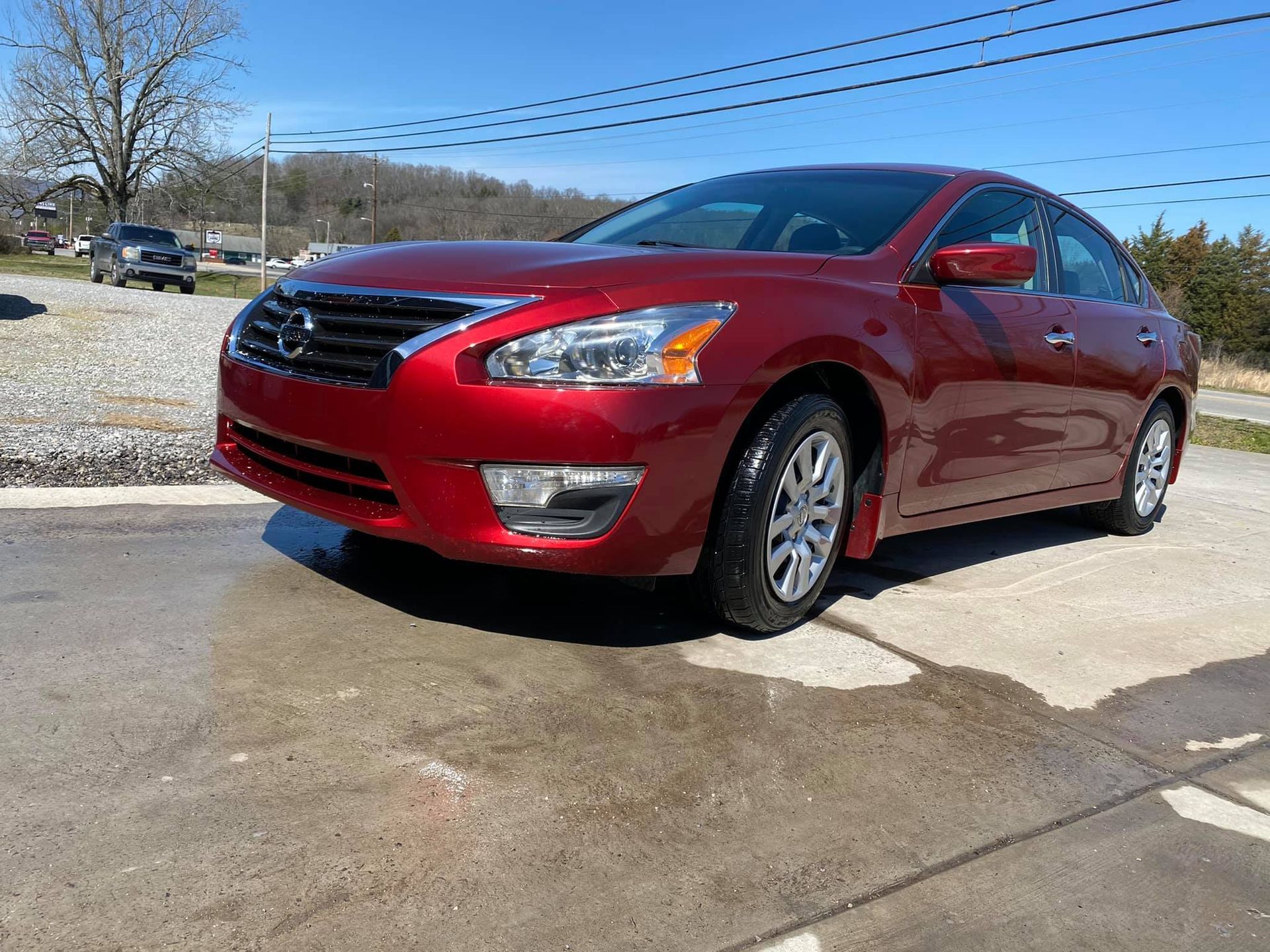 A red nissan altima is parked on the side of the road.