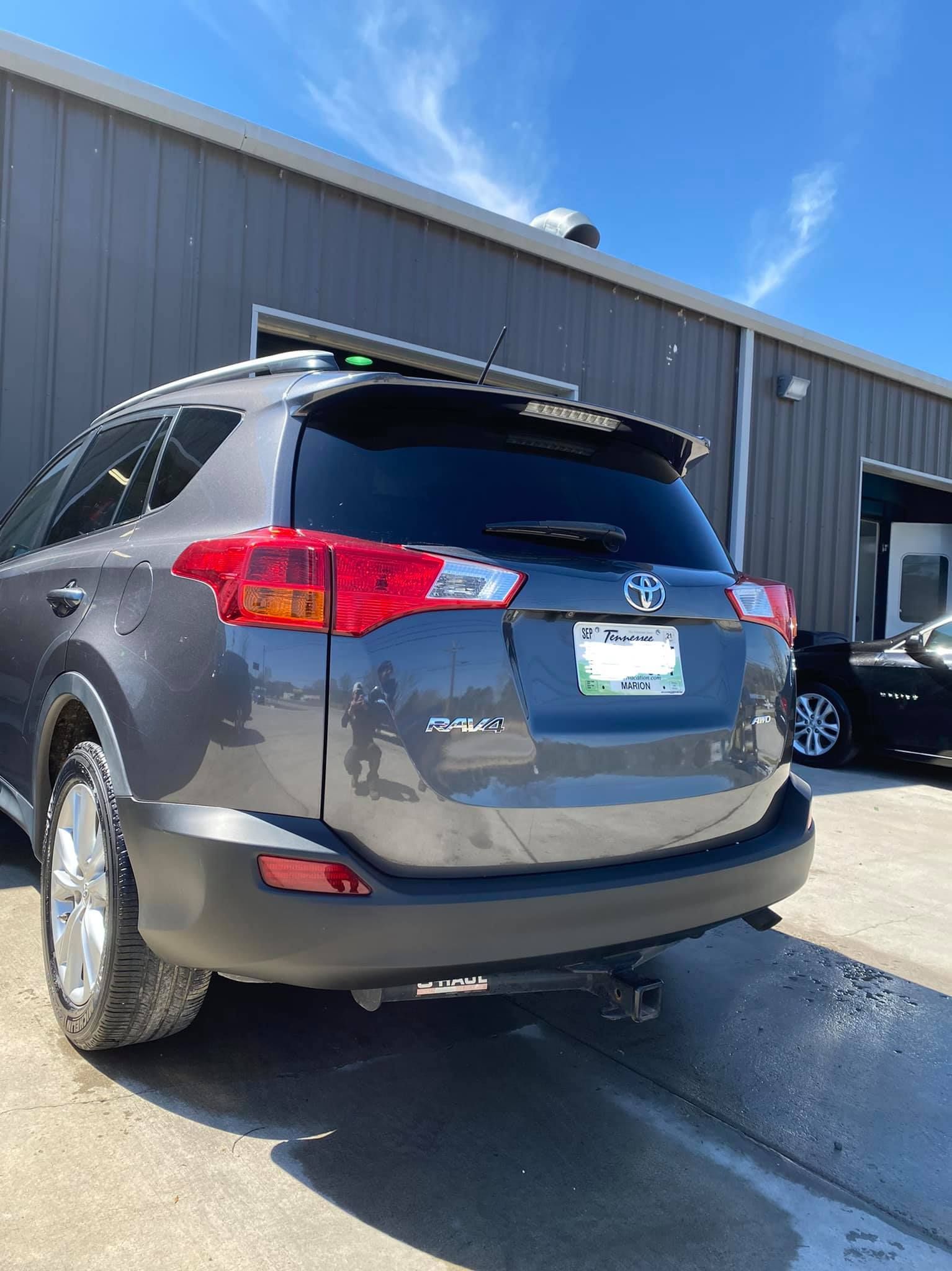 A gray toyota rav4 is parked in front of a building.