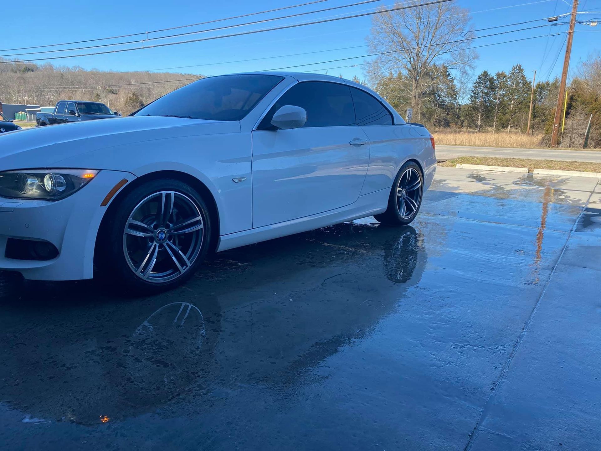 A white bmw is parked in a parking lot.