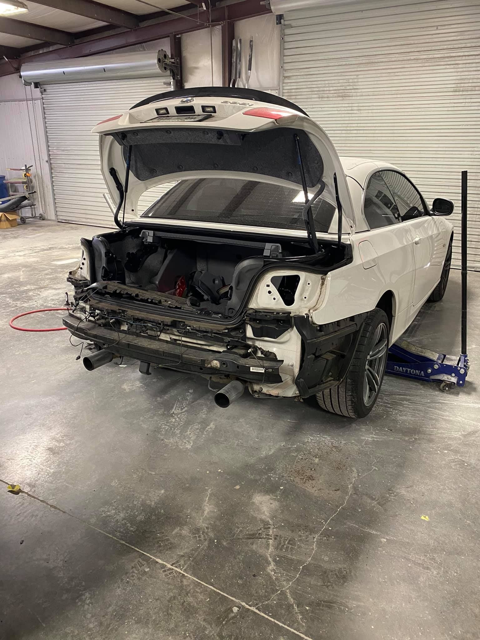 A white car with the trunk open is sitting in a garage.