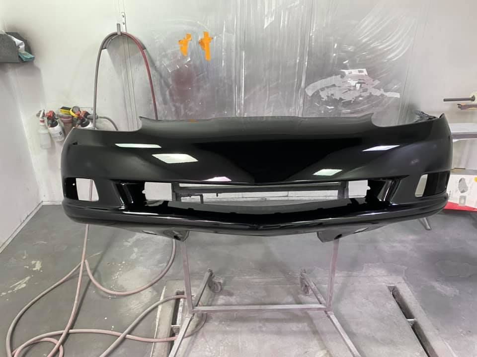 A black bumper is sitting on a stand in a garage.