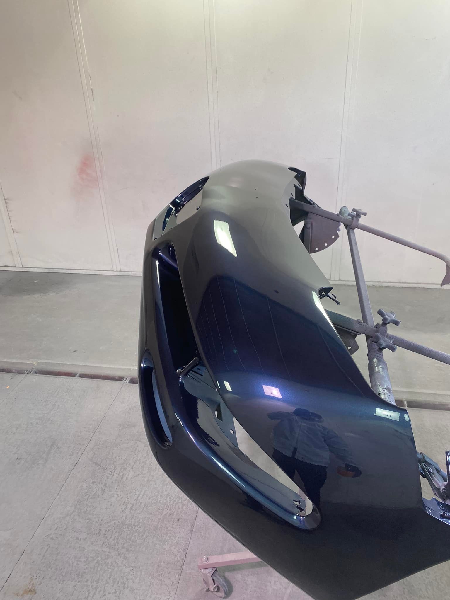 A black car bumper is sitting on a stand in a garage.