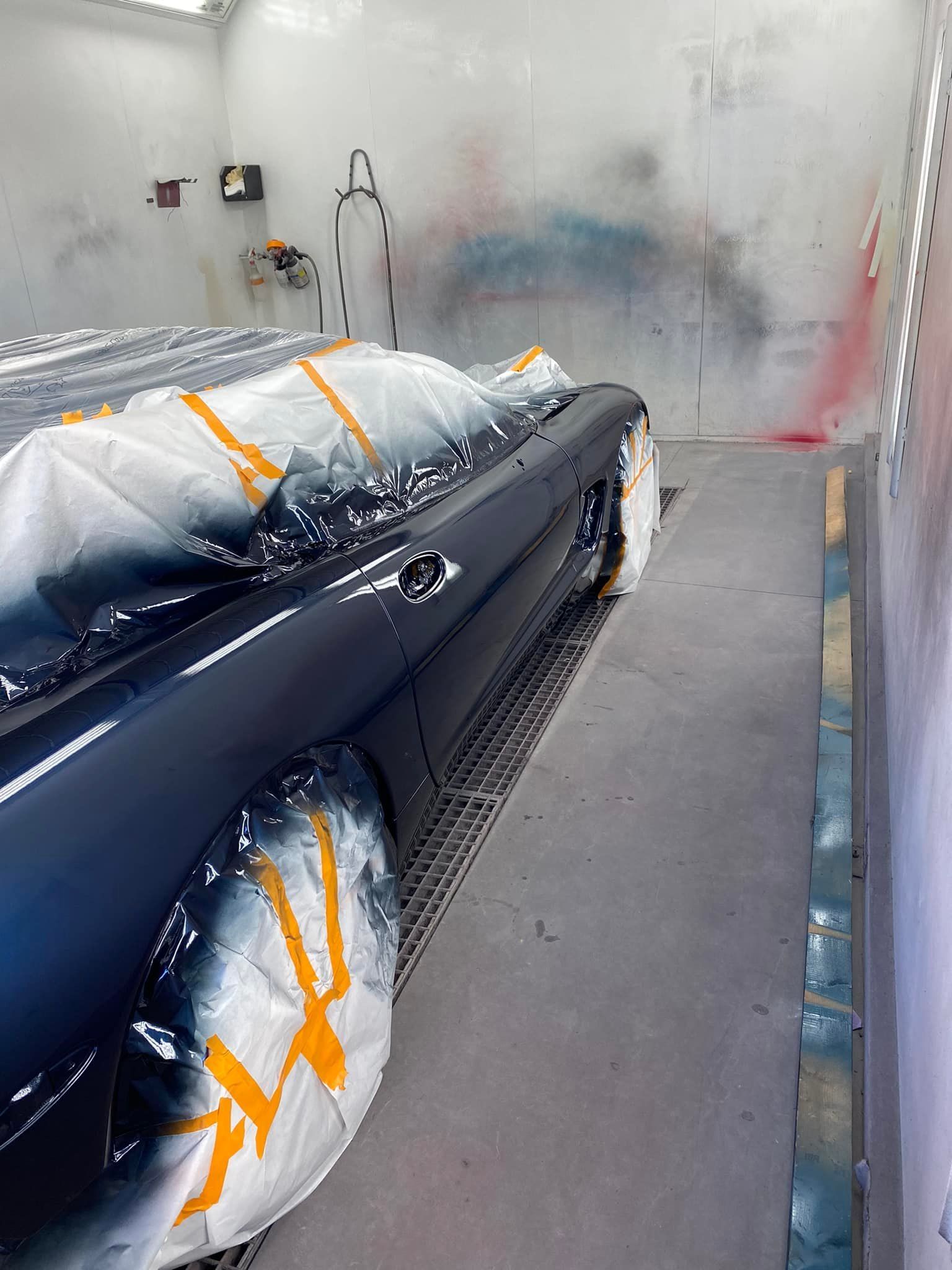 A car is being painted in a paint booth.