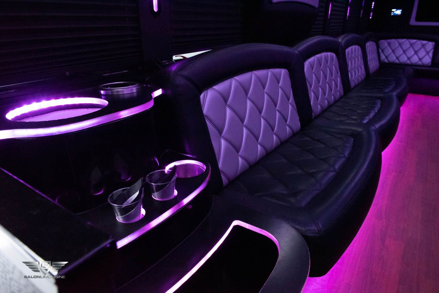 The inside of a limousine with purple lights on the seats.