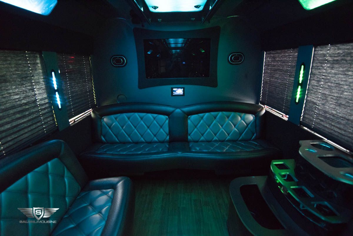 The inside of a limousine with a couch and a television.