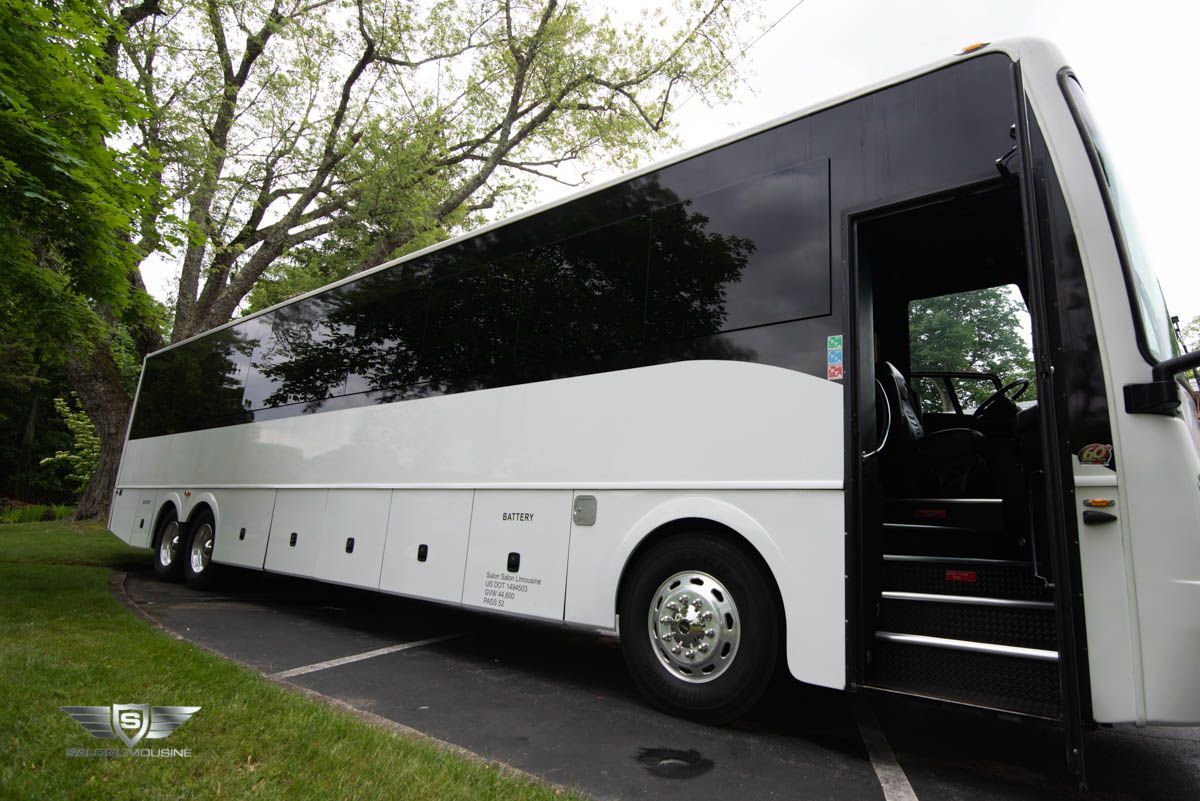 A white bus with the door open is parked on the side of the road.