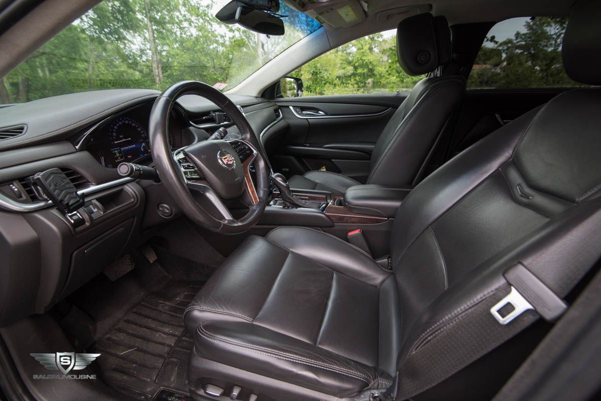 The interior of a black car with leather seats and a steering wheel.