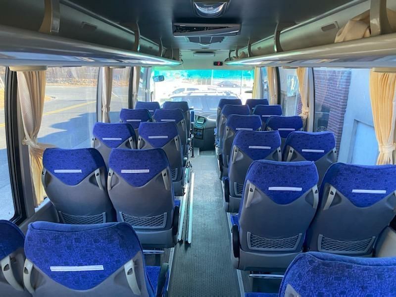 The inside of a bus with blue seats and a ceiling fan.
