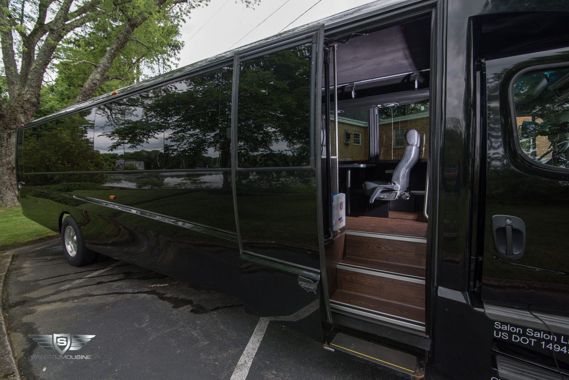 A black bus is parked in a parking lot with the door open.