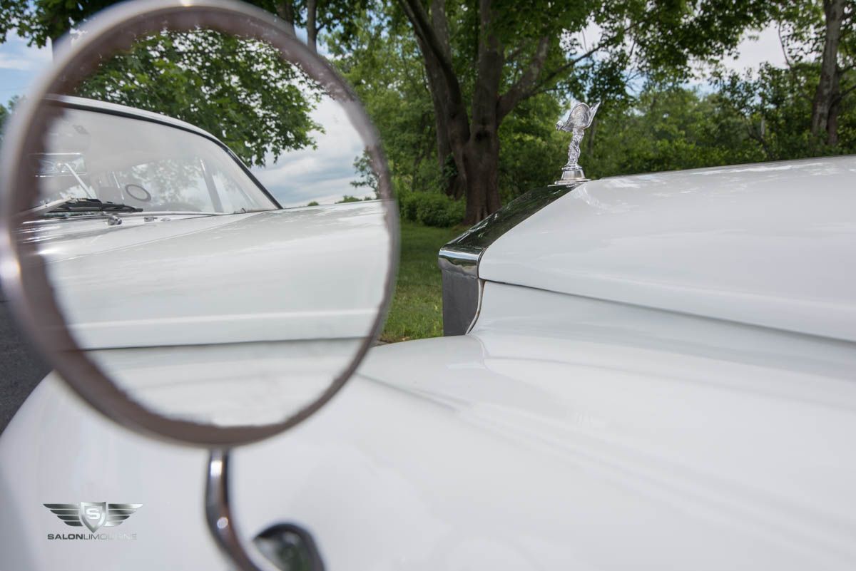 A white car is reflected in a rear view mirror.