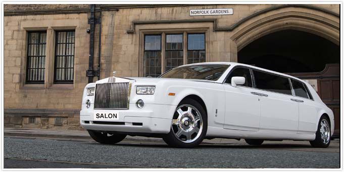 A white limousine is parked in front of a building.