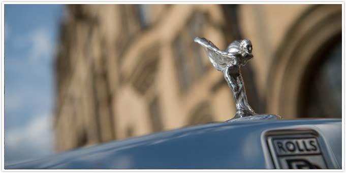 A silver rolls royce car with a statue on top of it