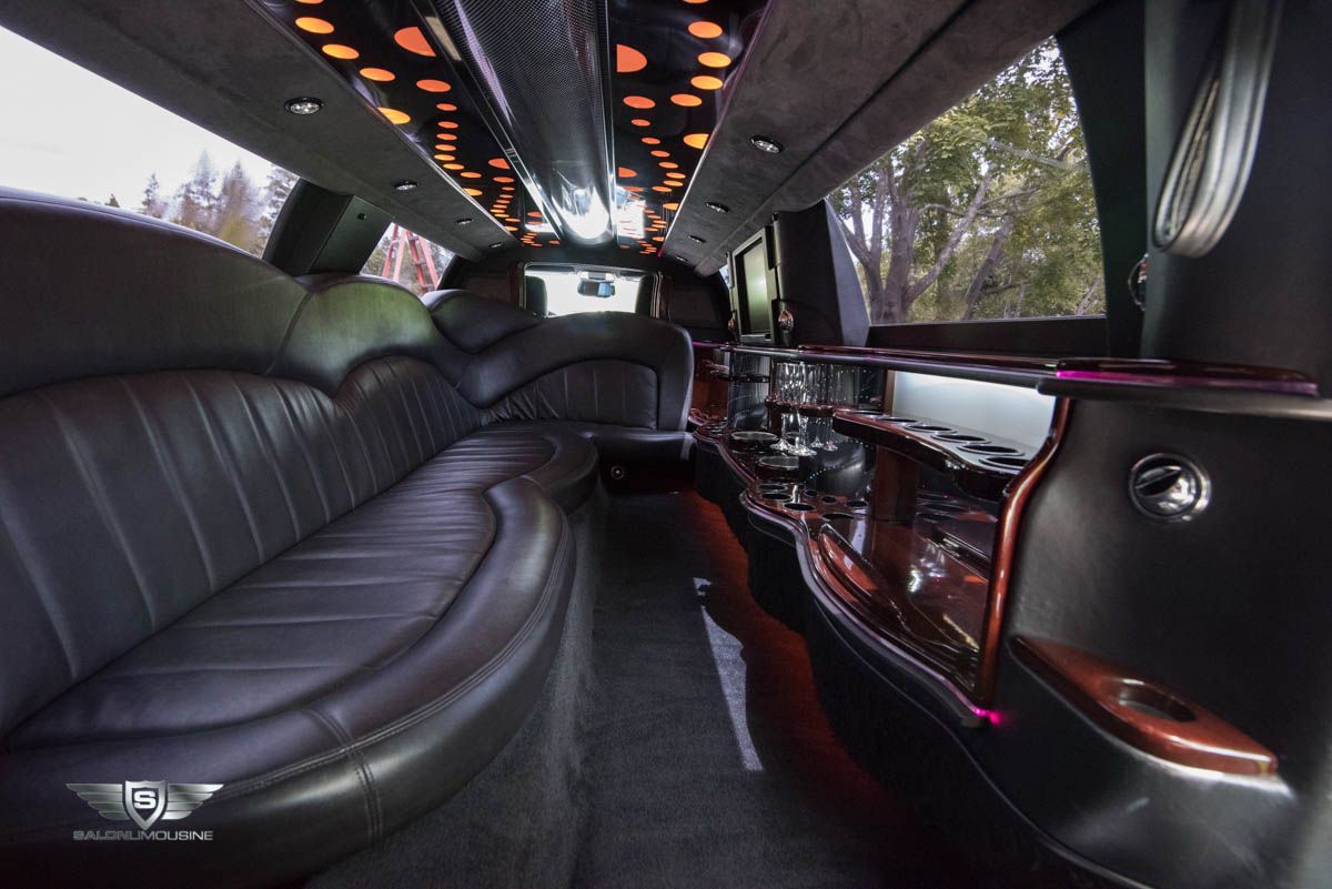 The inside of a limousine with a long couch and a bar.