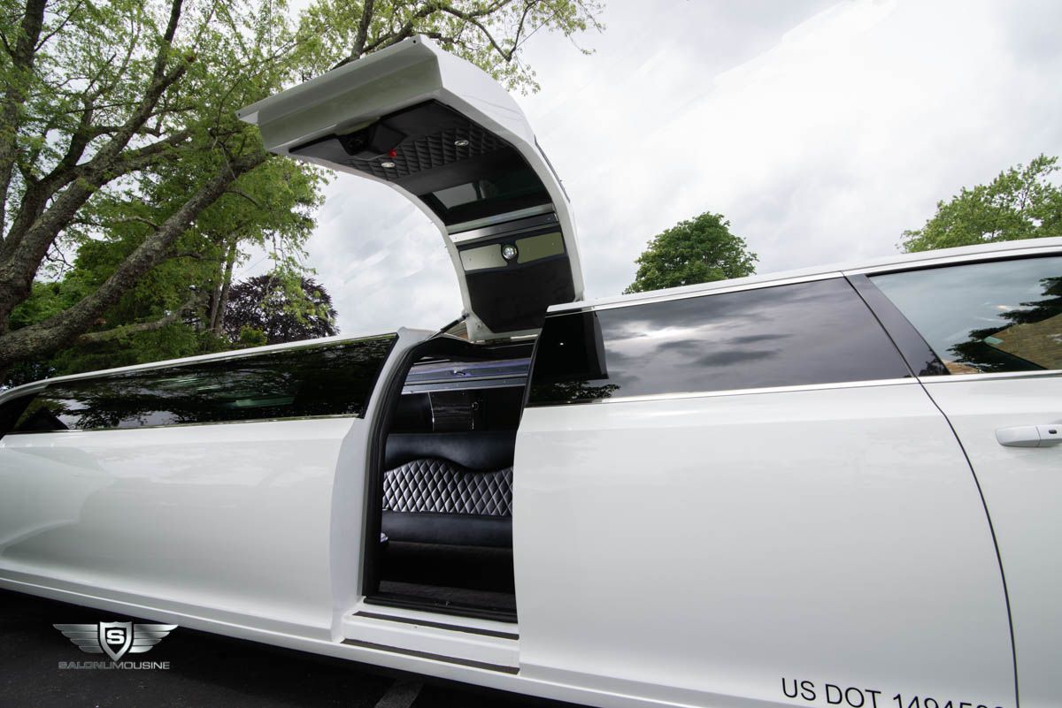 A white limousine with the door open is parked in a parking lot.