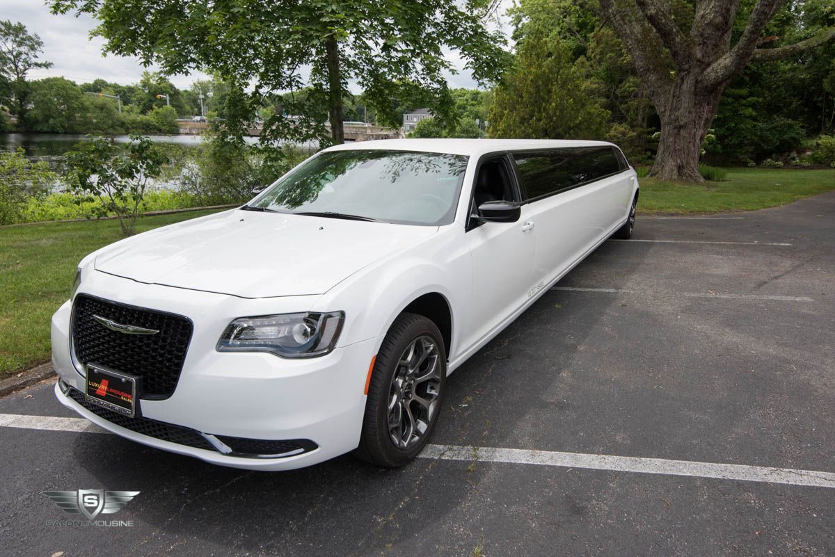 A white limousine is parked in a parking lot.