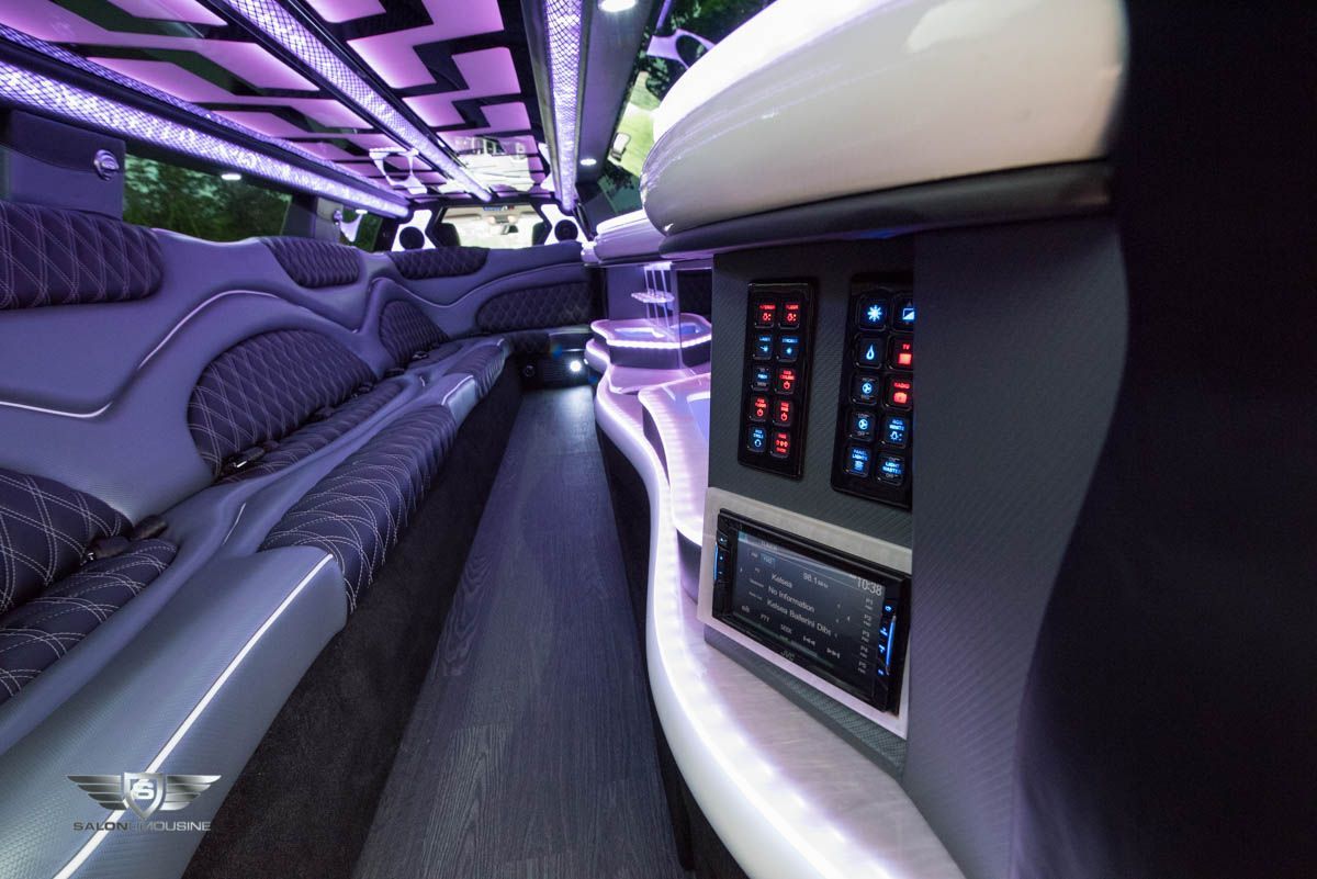 The inside of a limousine with purple lights on the ceiling.
