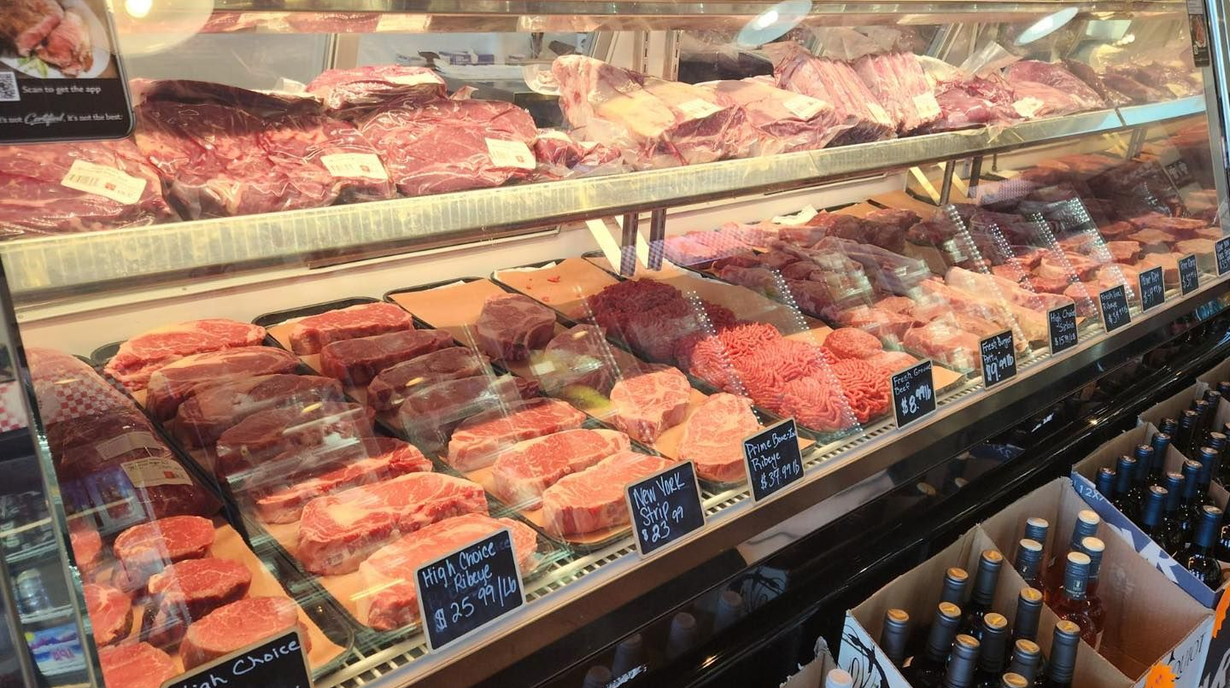 Raw meat cuts with wine, shallot, garlic, and herbs on a wooden cutting board.
